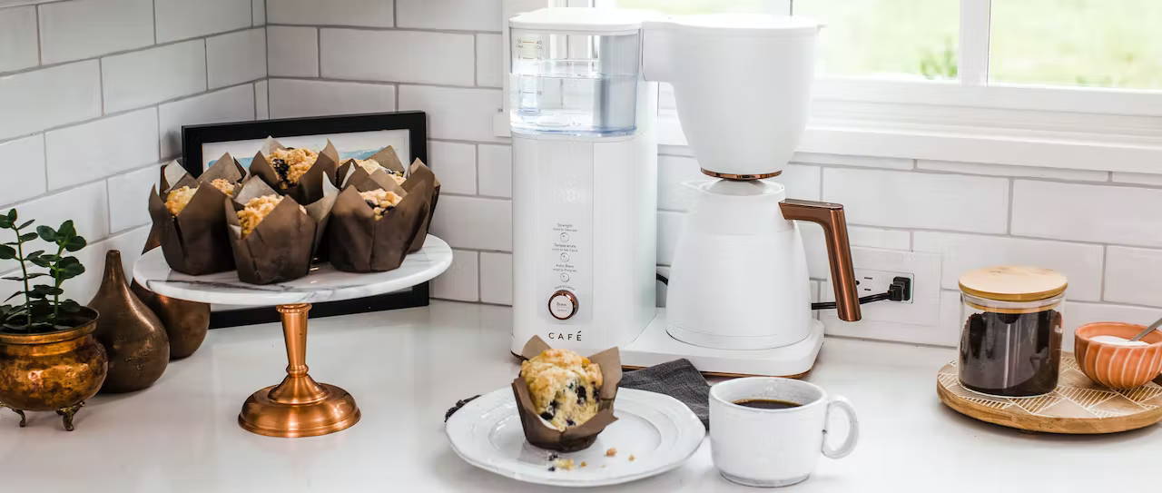 Matte white cafe coffee maker on counter with blueberry muffin