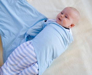 Baby with one arm in a miracle blanket swaddle
