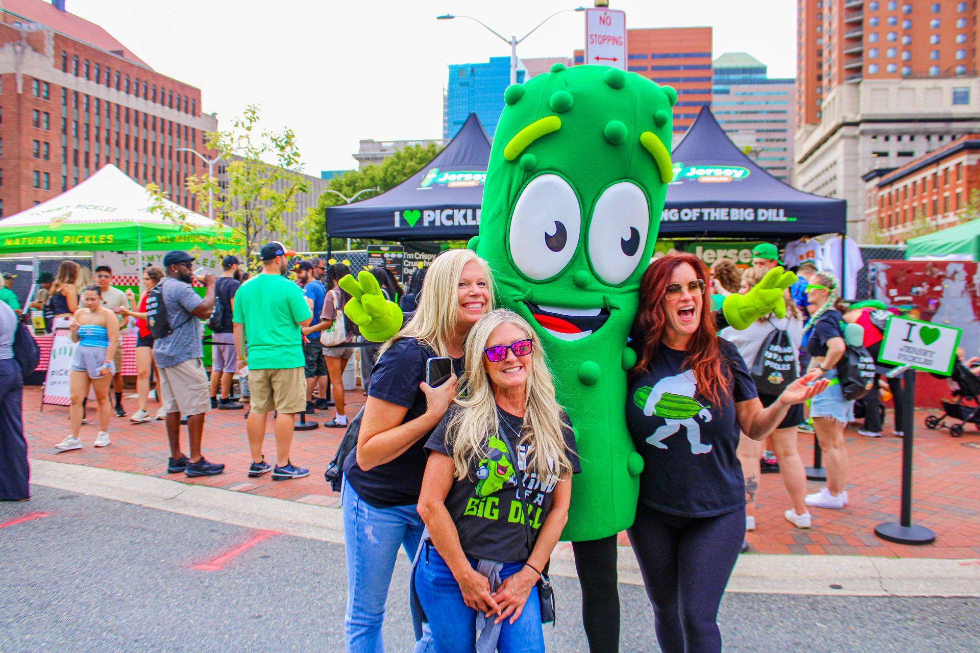 Three friends pose with the Jersey Pickles mascot at the Jersey Pickles 'King of The Big Dill' vendor activation at The Big Dill pickle festival, Power Plant Live!, Baltimore Maryland 2025.