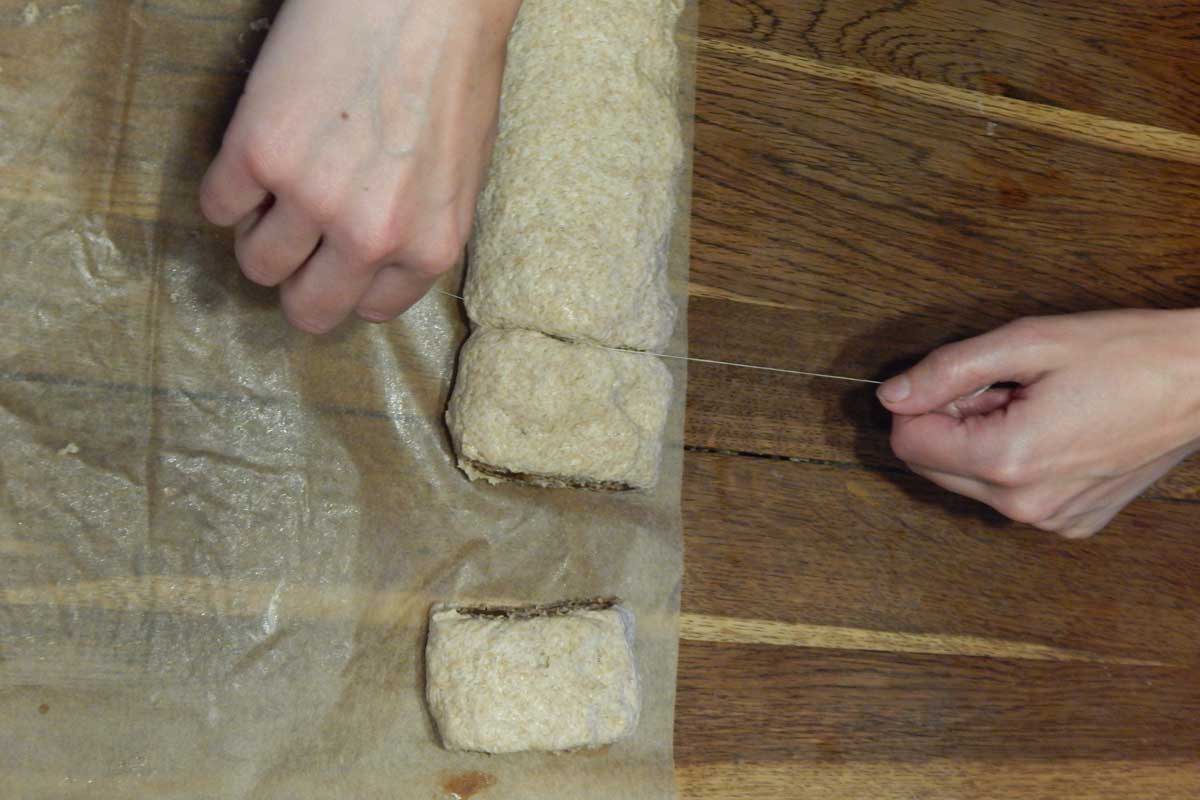 Baker using dental floss to cut the roll into pieces