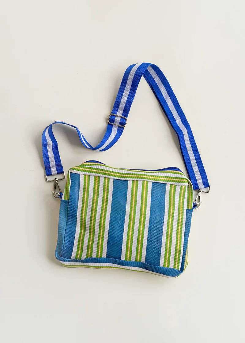 A blue, white, green and yellow striped cross body bag with matching strap