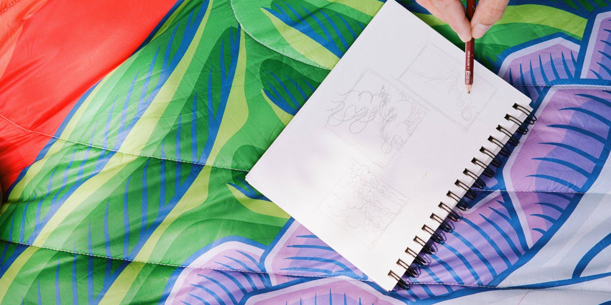 Close up of Aaron Kai's notebook as he draws a sketch - showing off the bold and bright colors of the Hokusai Great Wave Rumpl blanket