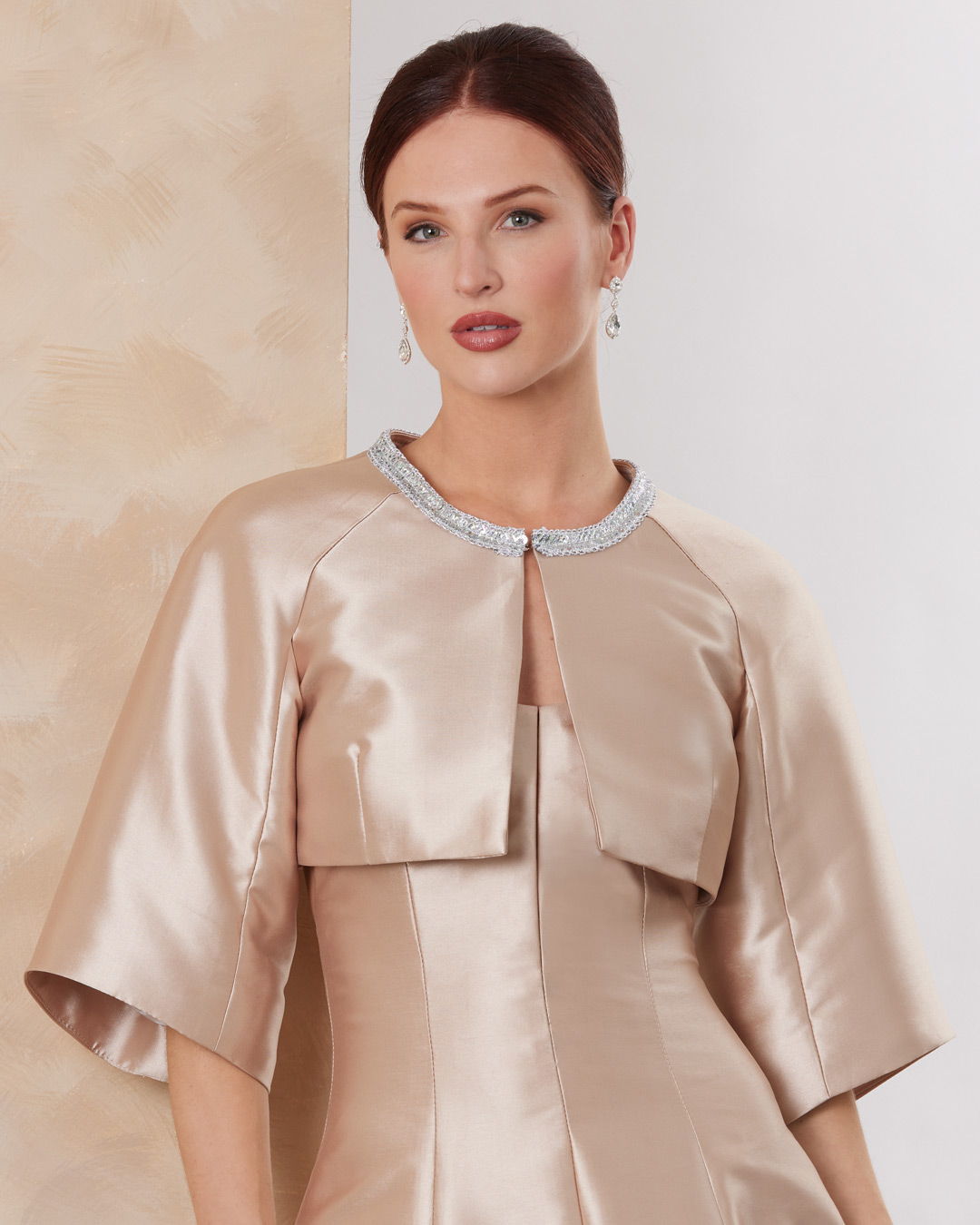 Woman wearing a stylish beige dress with a cropped jacket.