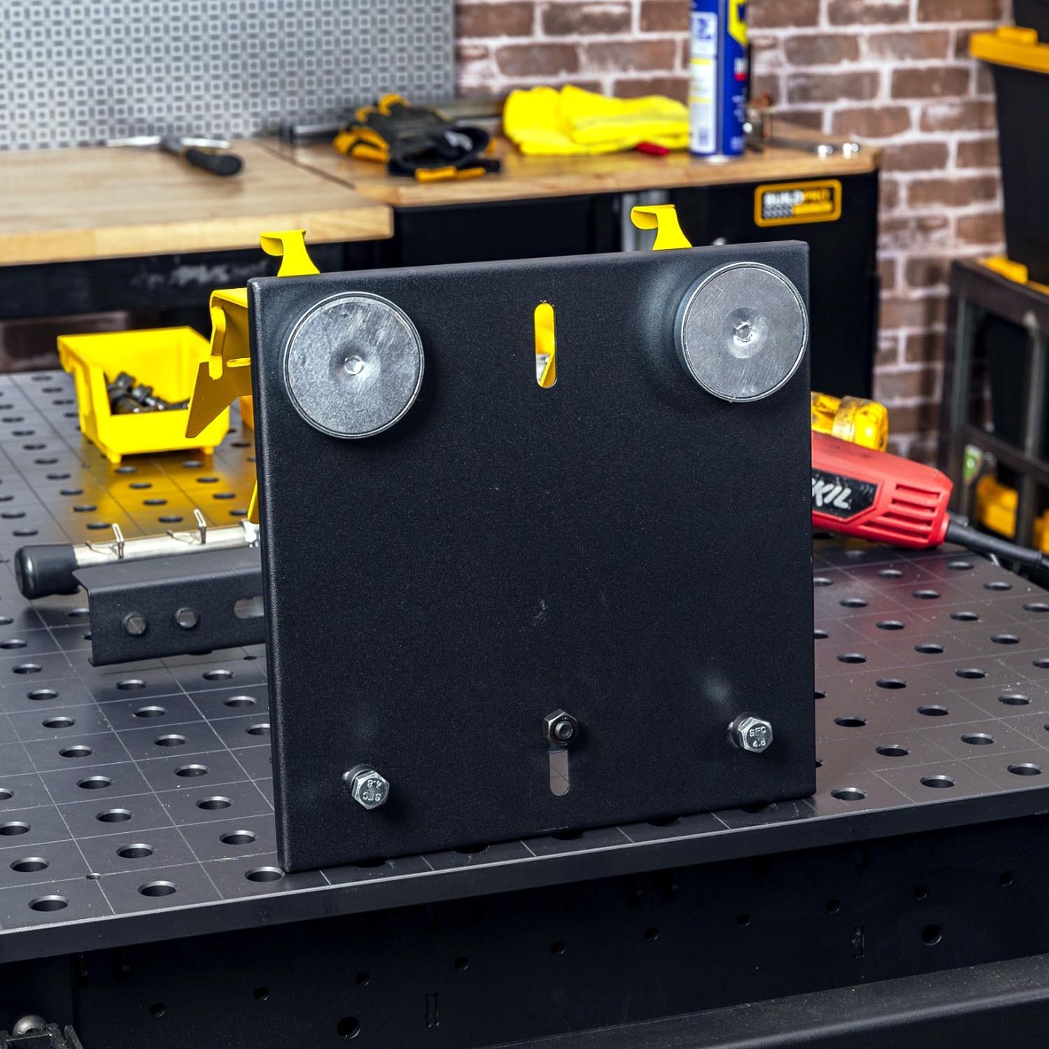 Black metal plate with wheels, mounted on a workbench.