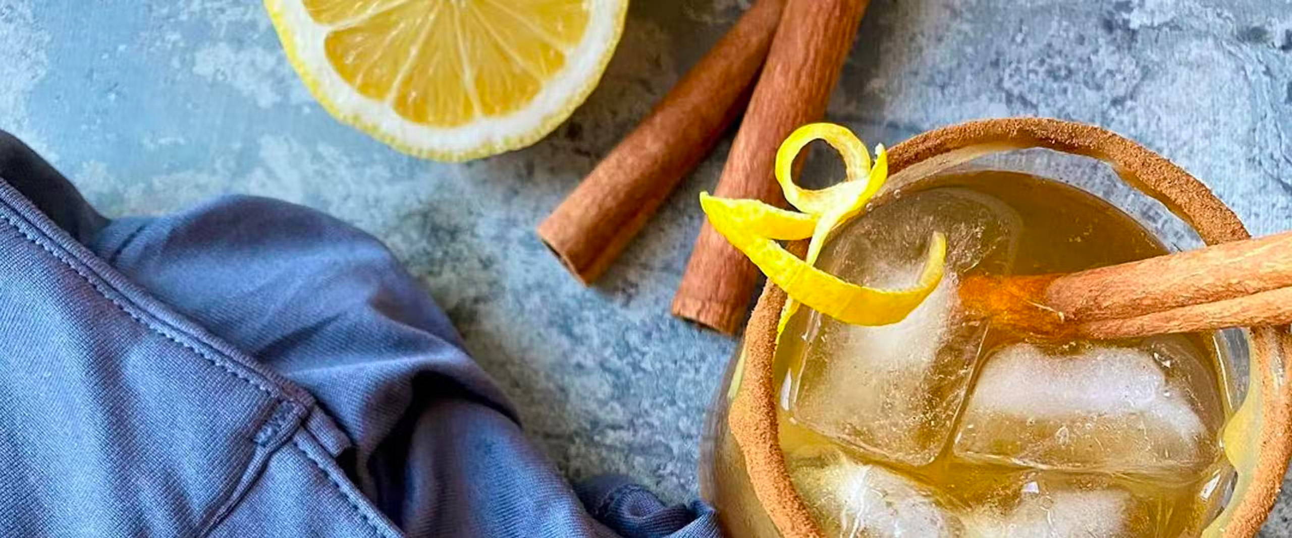 overhead view of a glass of bourbon maple leaf cocktail garnished with a lemon peel.