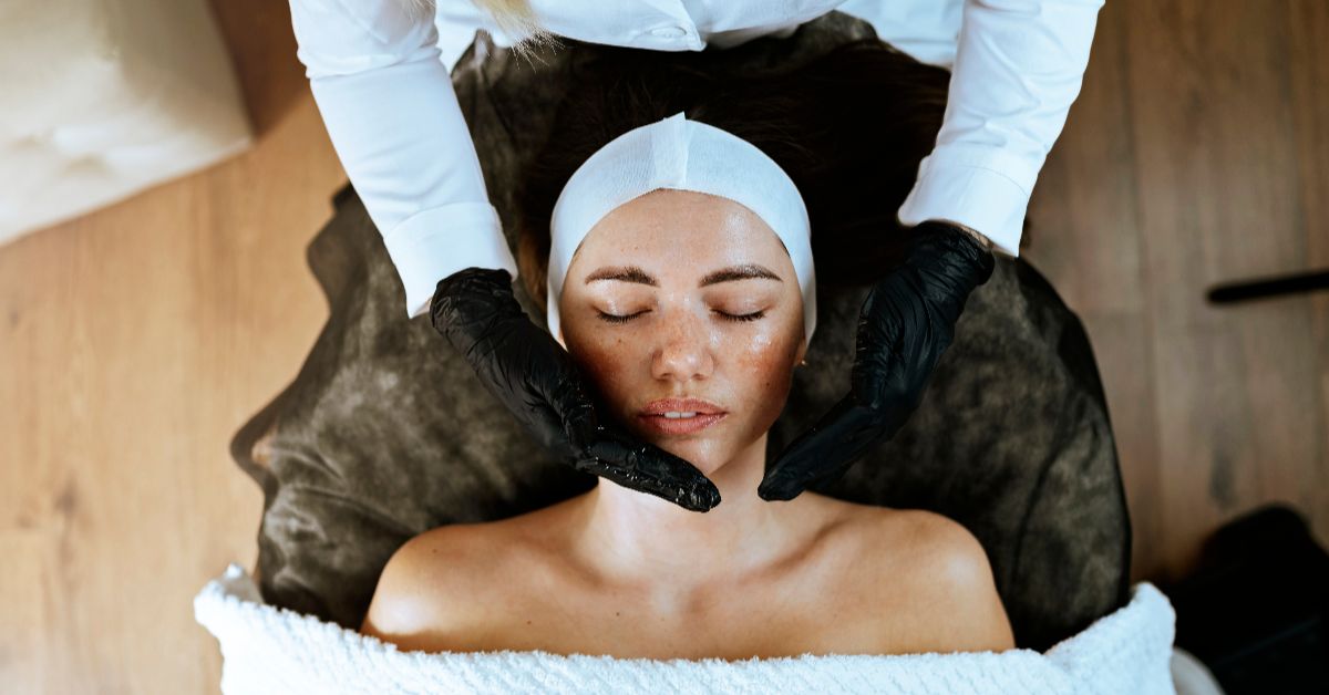 A woman receiving a facial treatment with a therapist's hands.