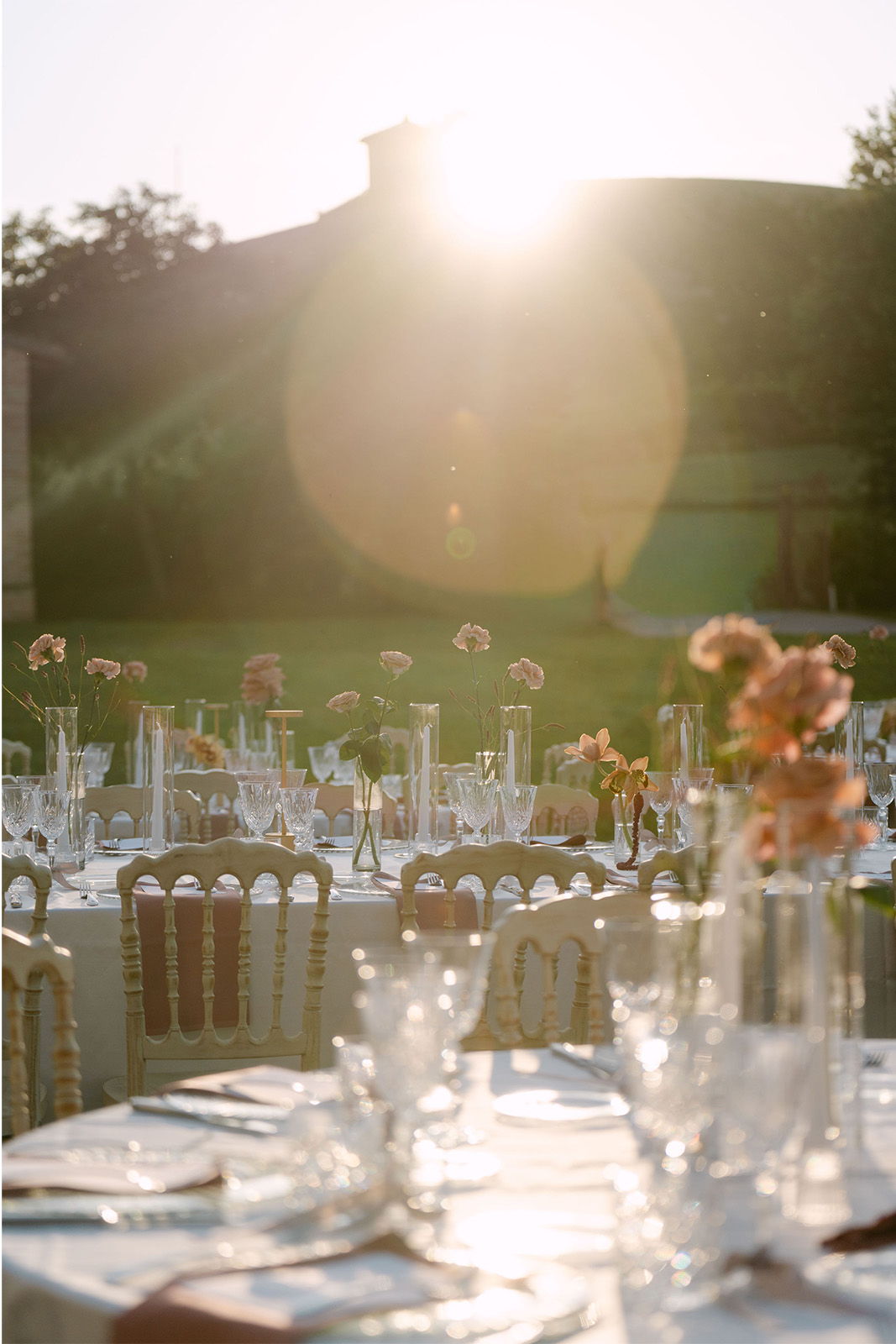 Elegant outdoor dining setup with floral arrangements and sunset backdrop.