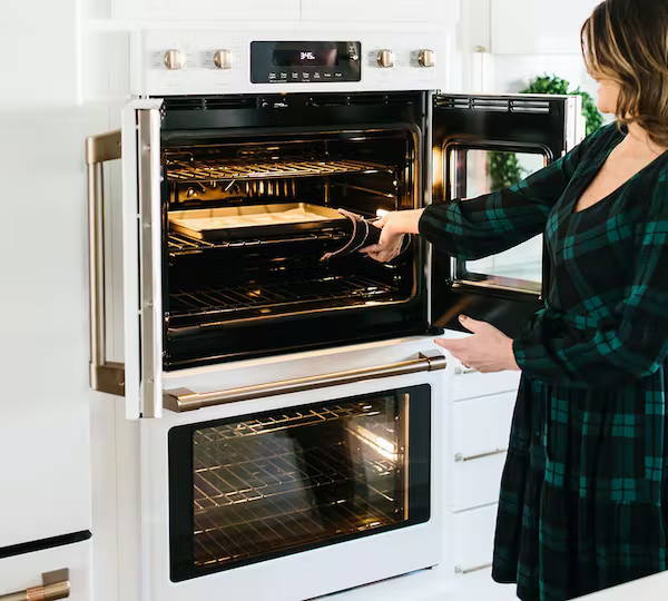 Woman pulling cookies out of wall oven