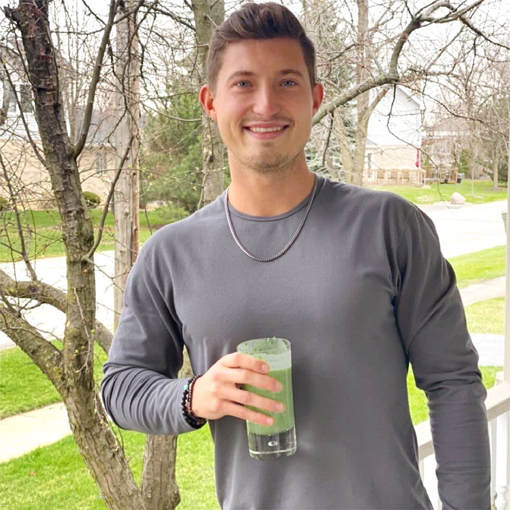 man holding a glass of daily greens