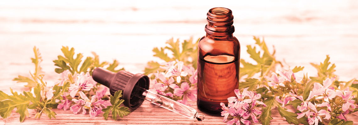 Amber glass bottle surrounded by flowers on a wooden surface.
