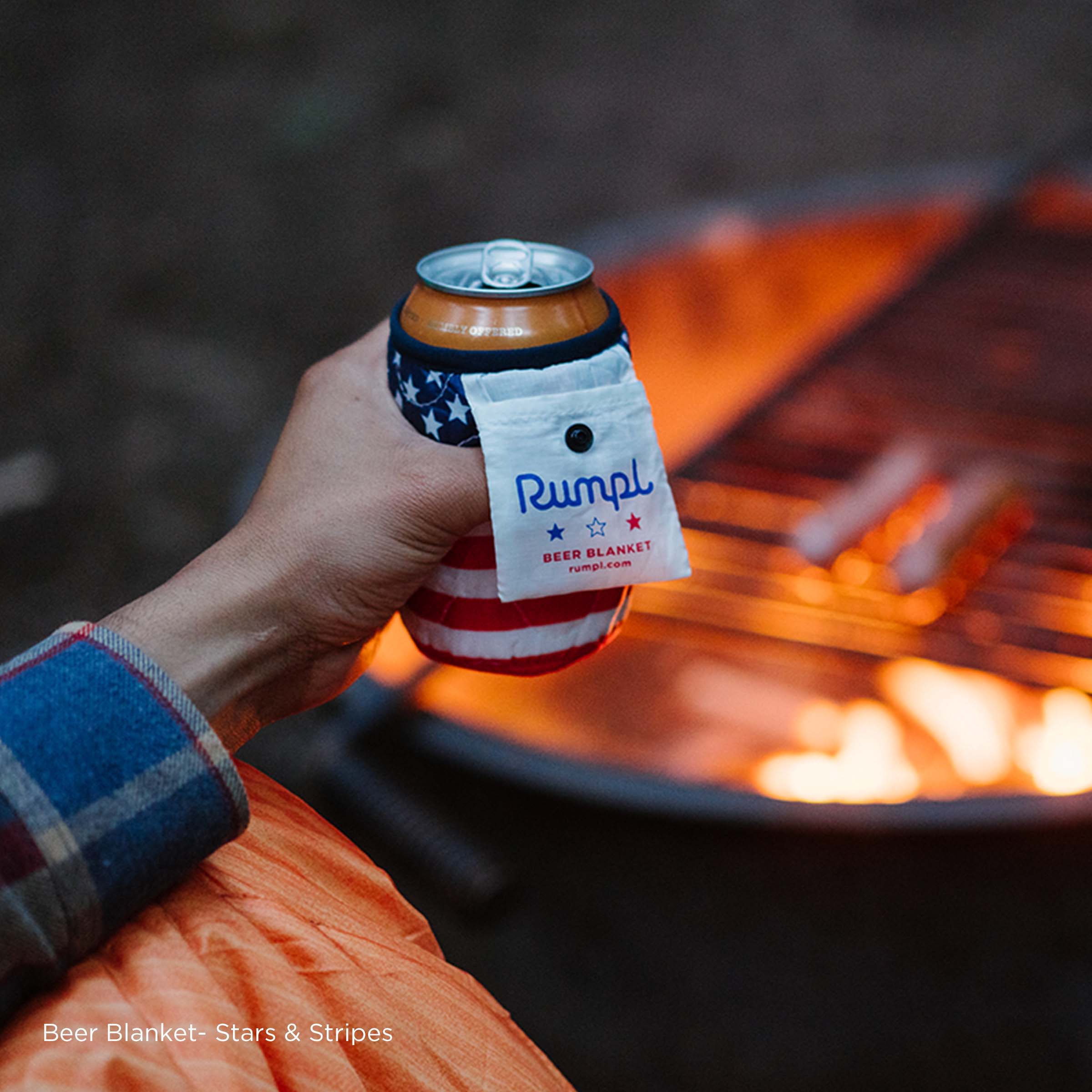 Person holding a Rumpl beer blanket next to a campfire