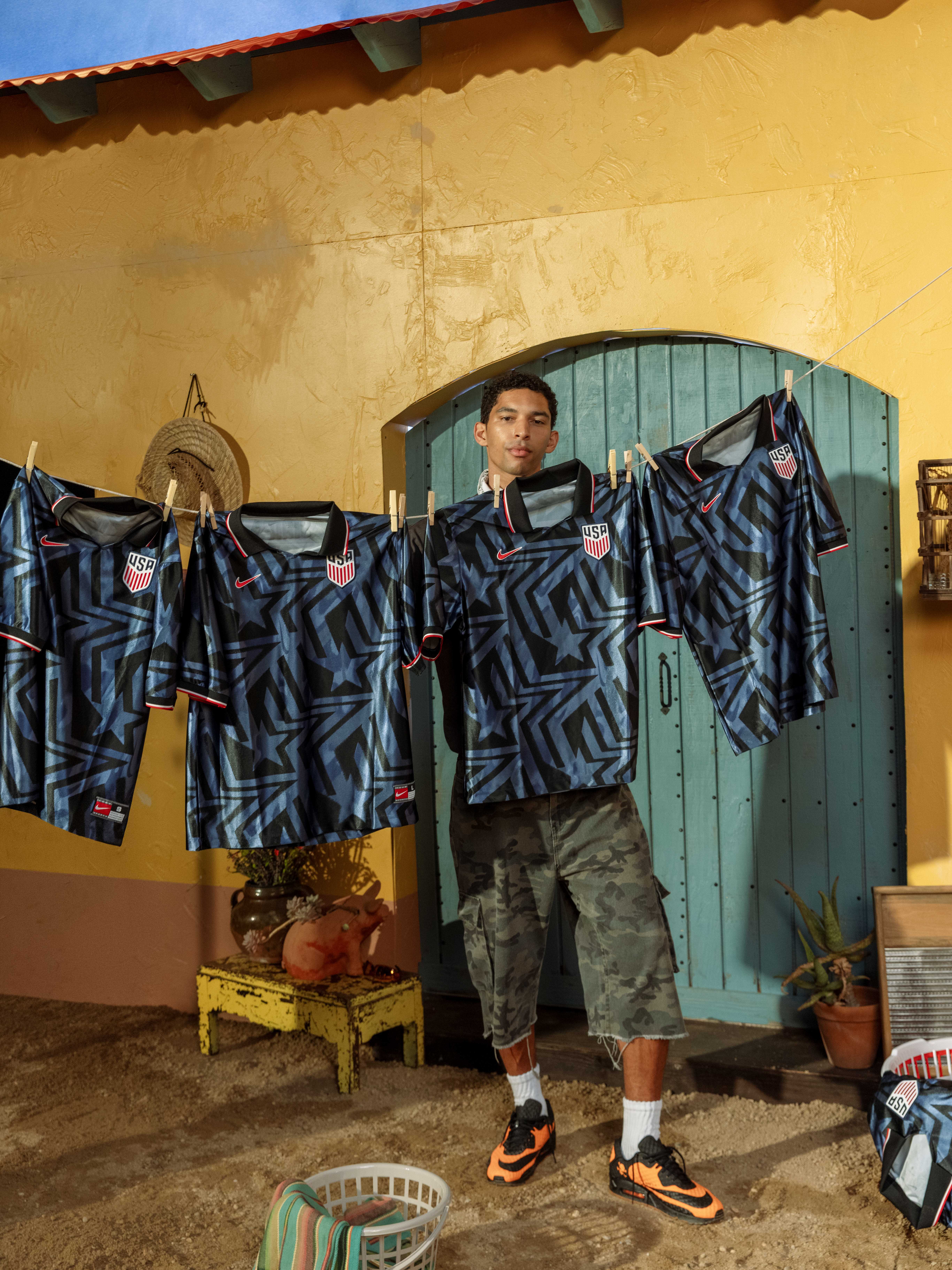 Person holding soccer jerseys on a clothesline in a colorful outdoor setting.