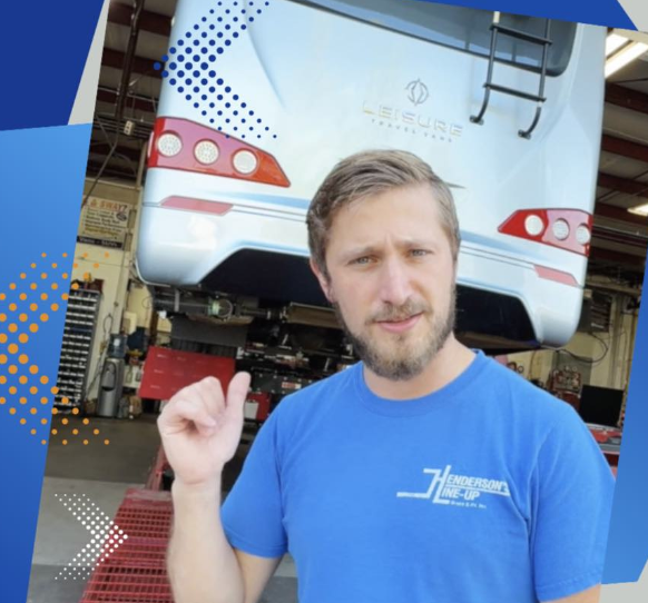 Man in blue shirt gesturing towards a bus in a garage.