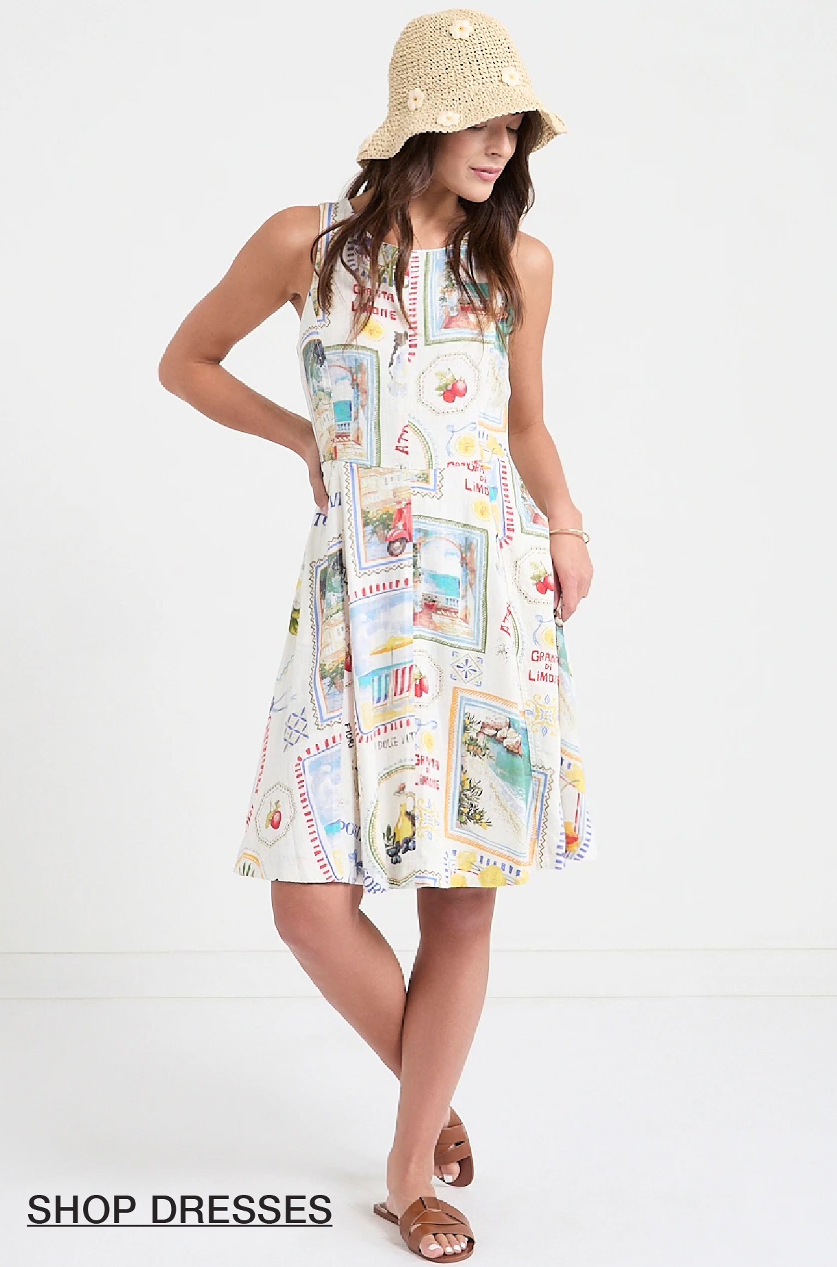 Woman in a colorful dress and hat, standing and smiling.
