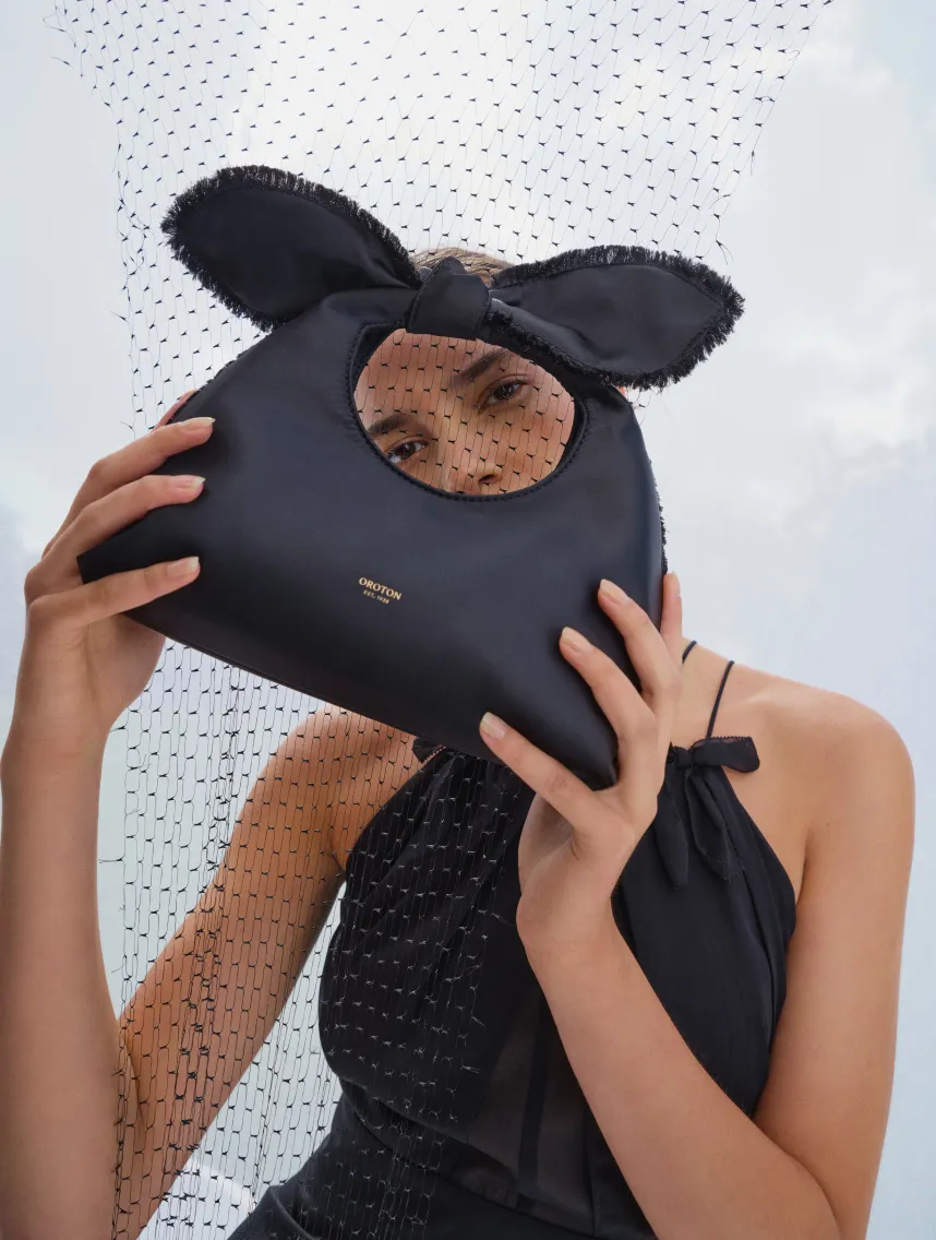 A person holding a black bag with ears, partially obscured by a net.