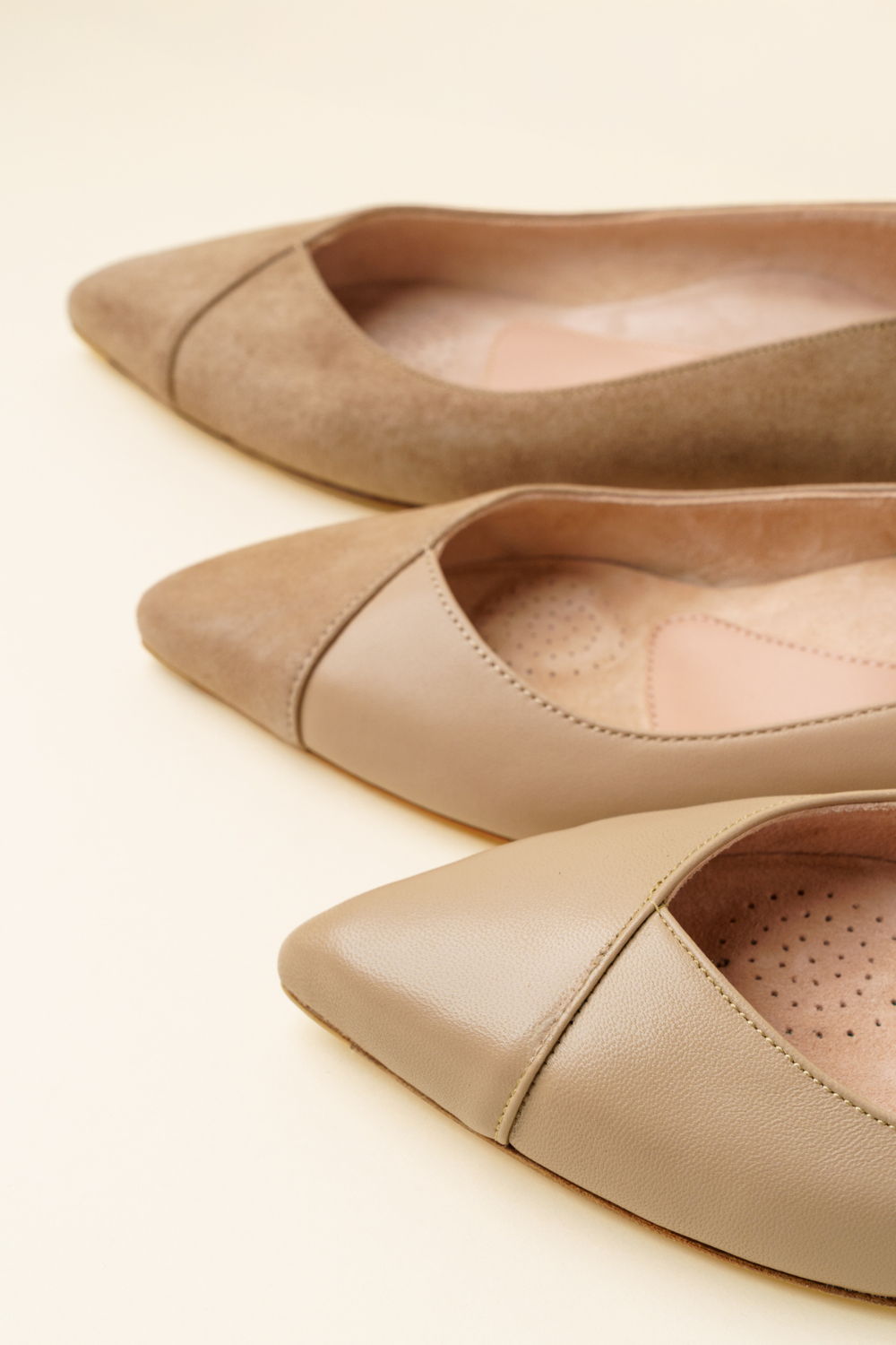 Three pairs of pointed-toe flats in various shades of beige.