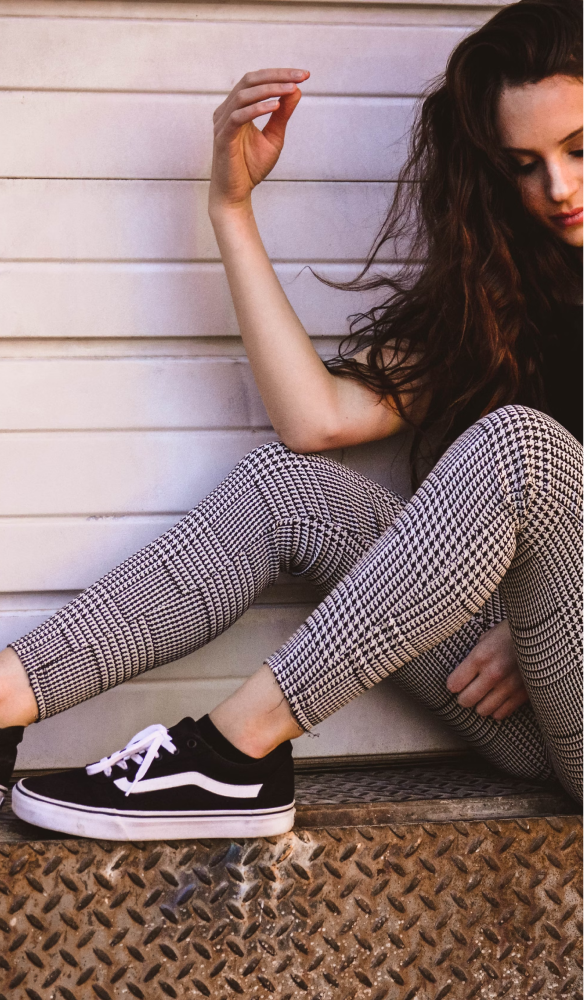 A woman sat on safety patterned metal showing off her black and white sneakers