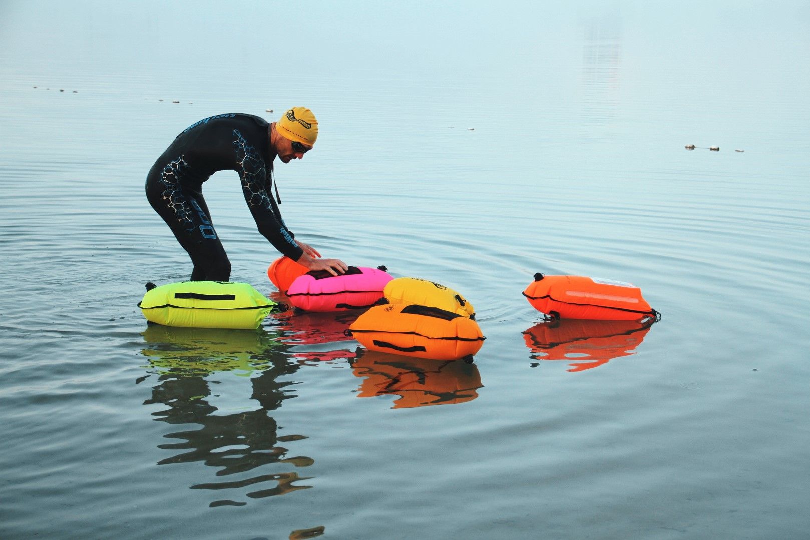 Ein Triathlet im Wasser mit verschiedenen farbigen Schwimmbojen.