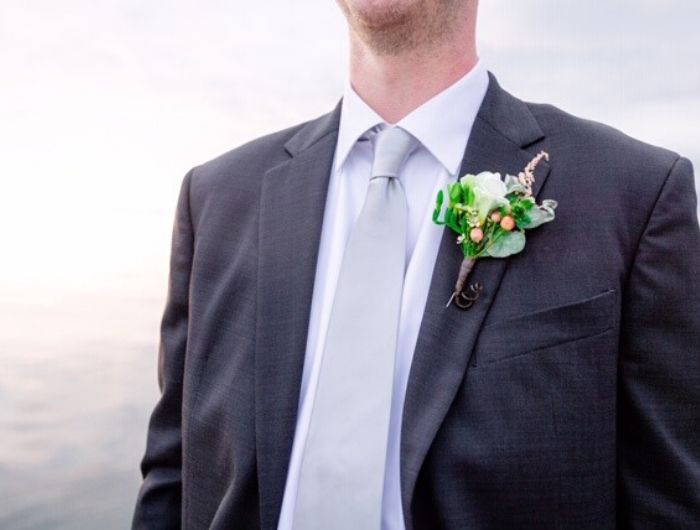 Man wearing a dark gray suit, silver tie and white boutonniere