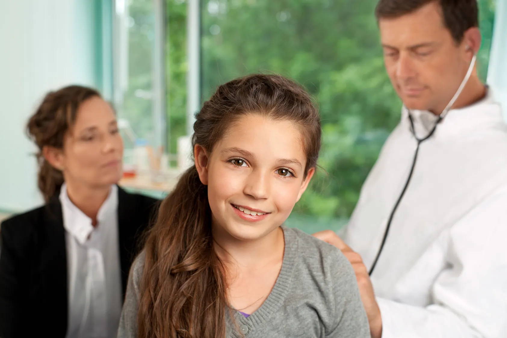 En jente er hos legen sammen med moren sin – legen undersøker henne med et stetoskop.