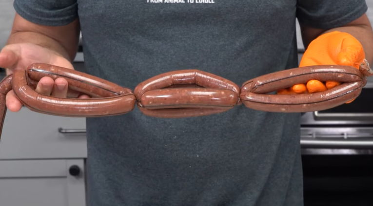 Person holding a long chocolate item and orange balls in hands.