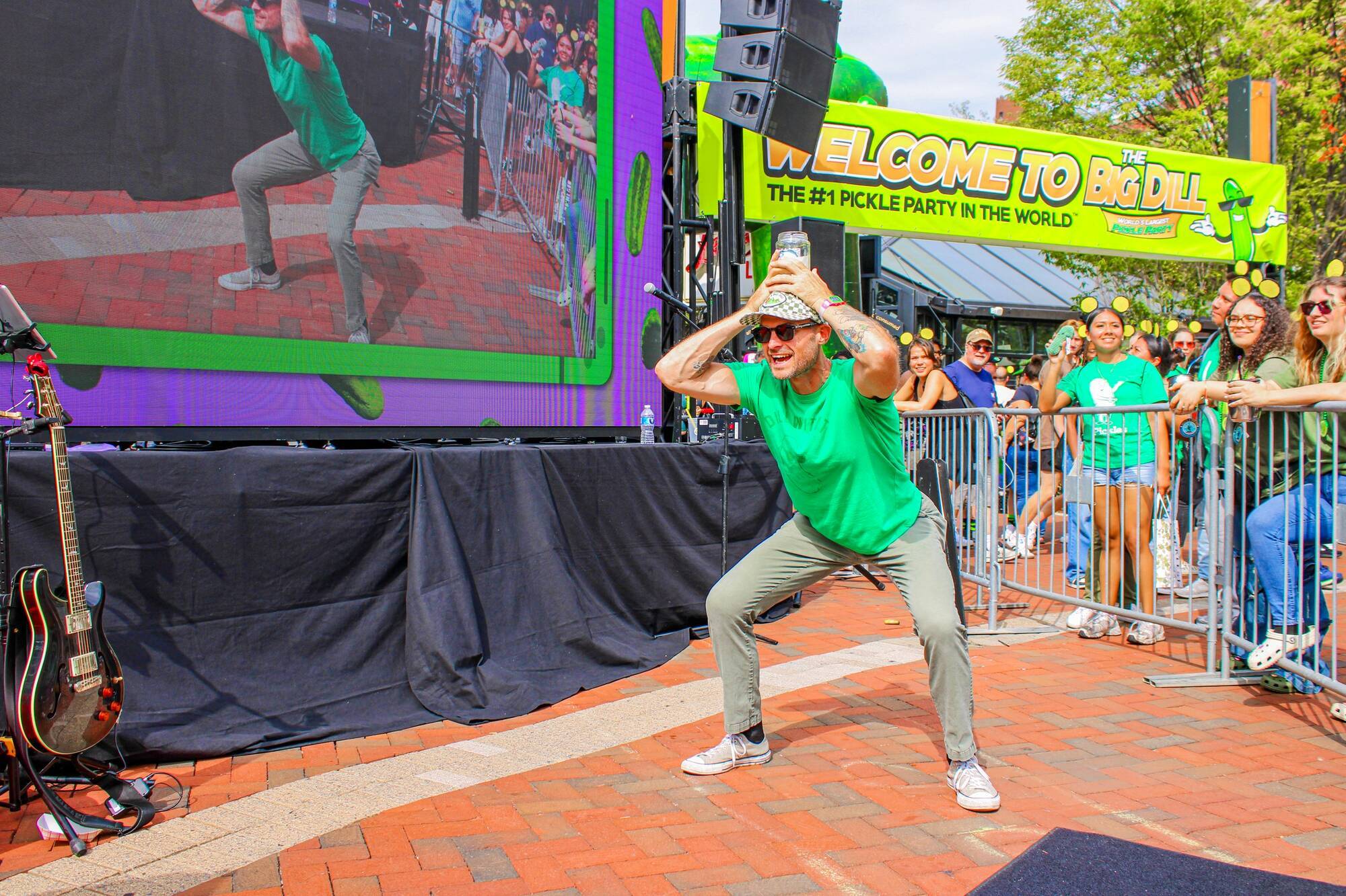Pickle Up! contestant balancing a pickle jar on his head on stage at The Big Dill® Baltimore 2025, the #1 Pickle Party in the World®
