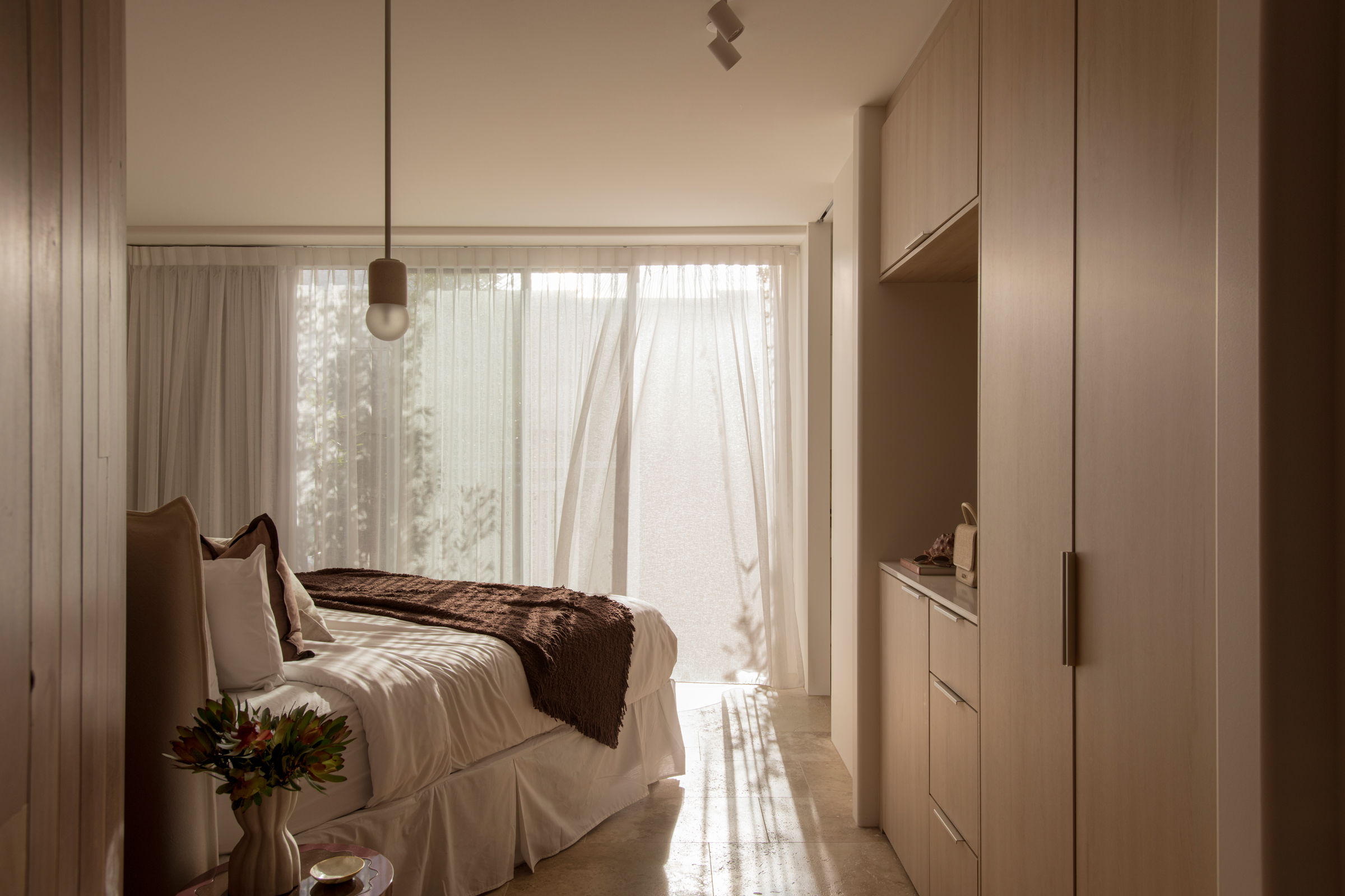 Cozy bedroom with natural light, soft bedding, and minimalistic decor.