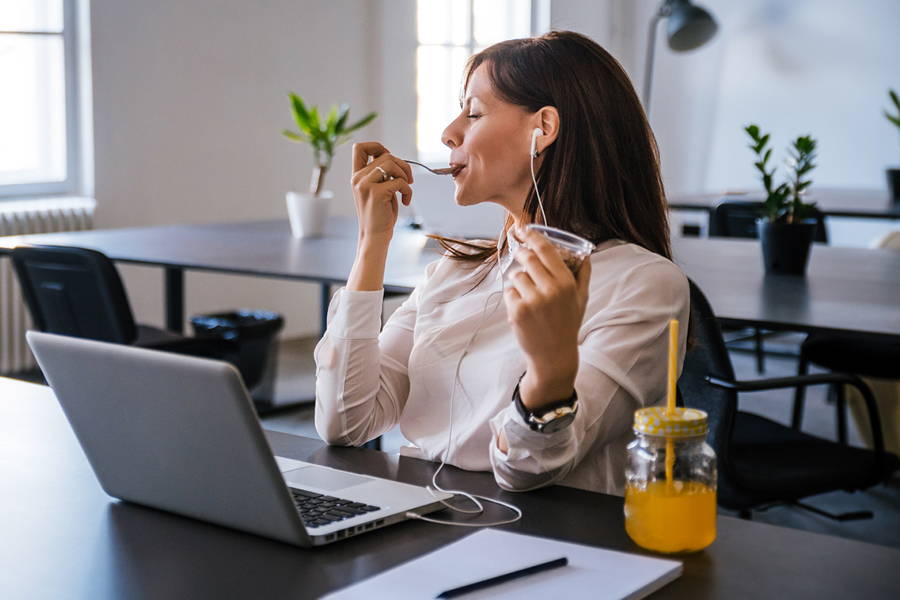 office worker enjoying a snack in front of laptop