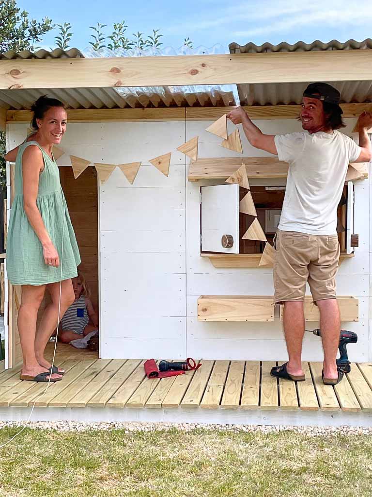Mum and Dad putting together their kids wooden cubby house kit