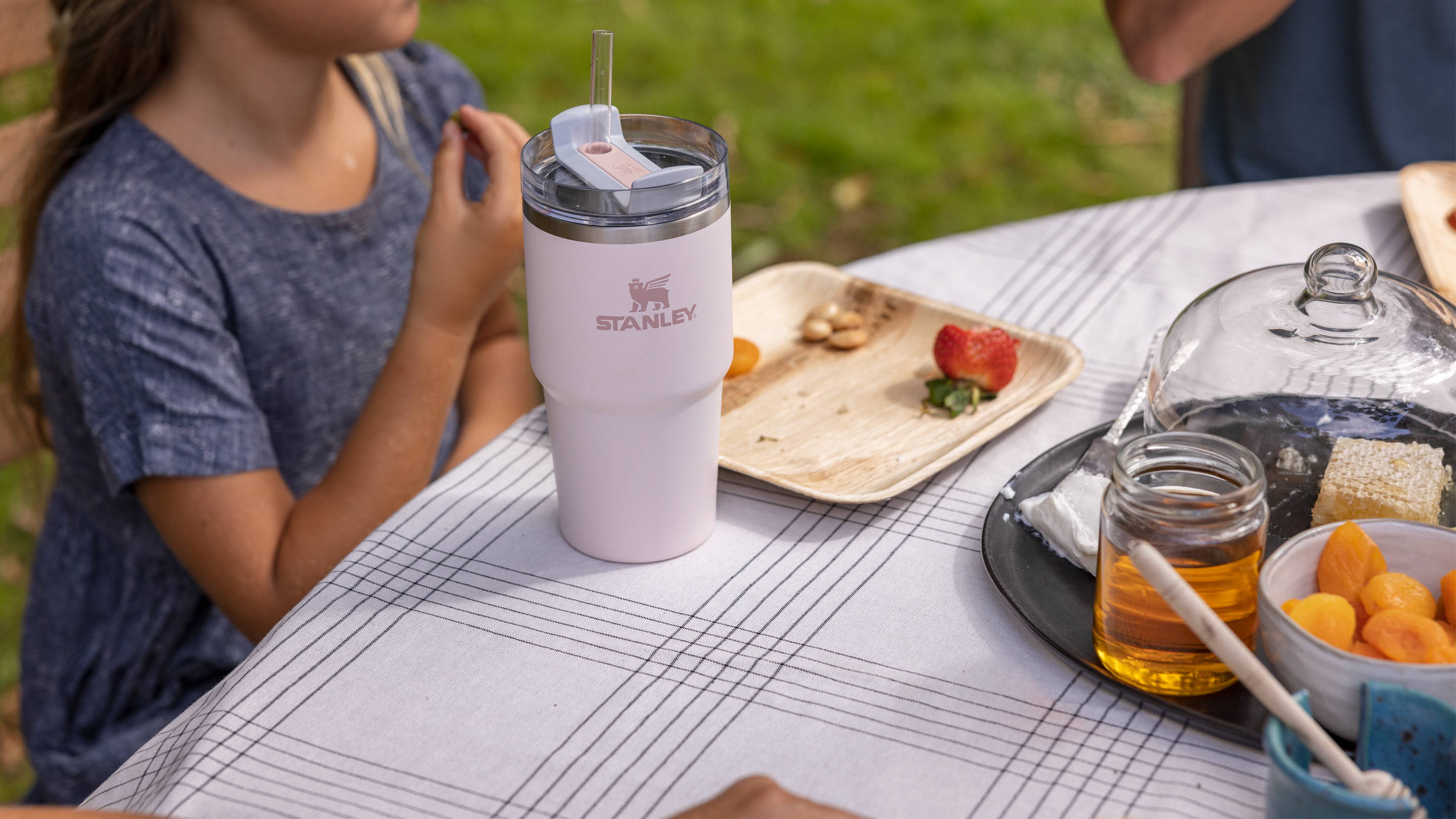 Kid eating outside at table with purple Stanley cup