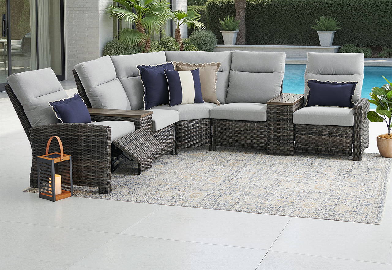 Outdoor patio furniture set near a pool with palm trees in the background.