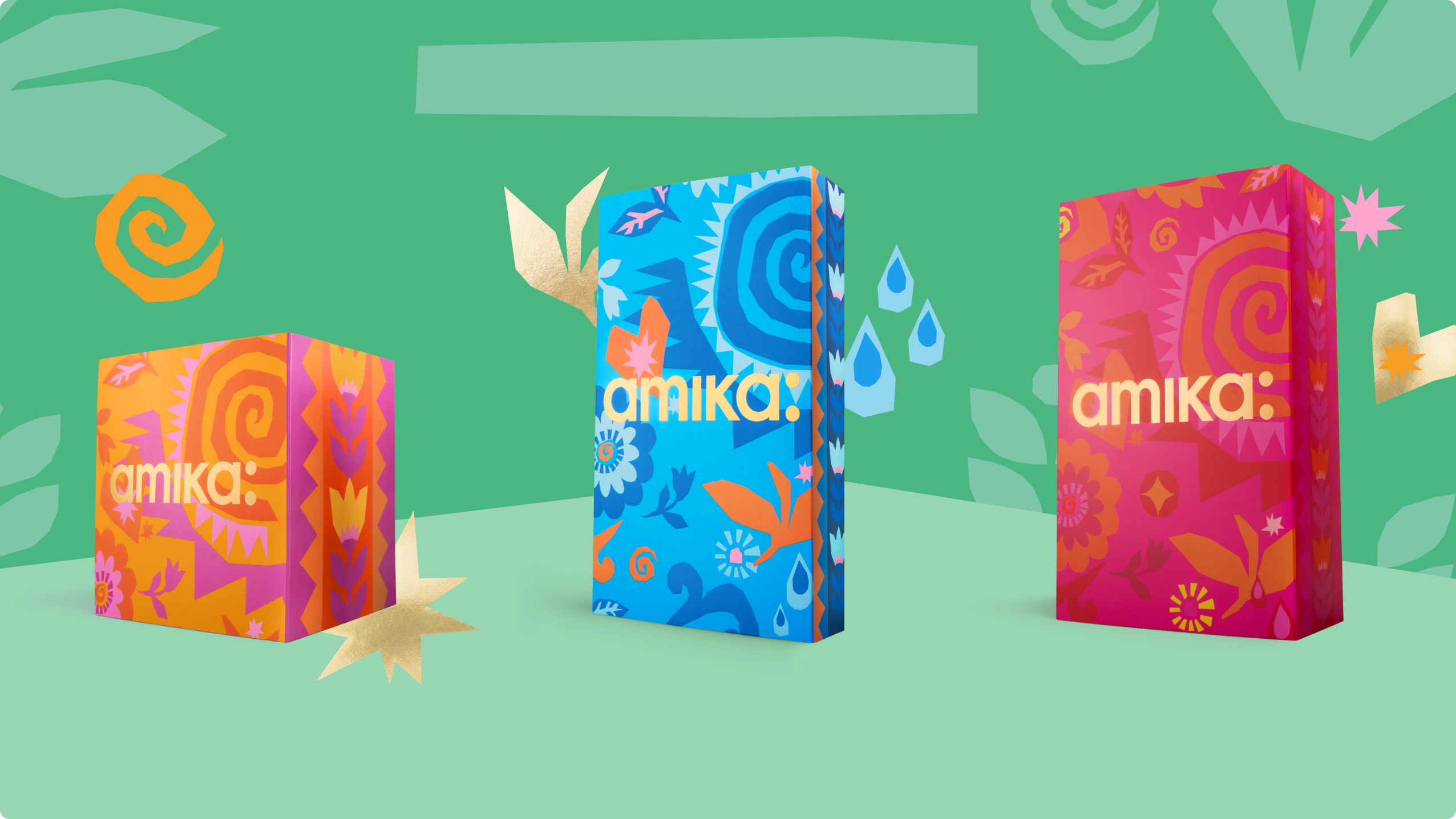 Three colorful Amika product boxes on a green background.