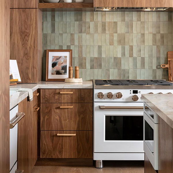 Wooden cabinetry and white professional range against a green tiled backsplash.