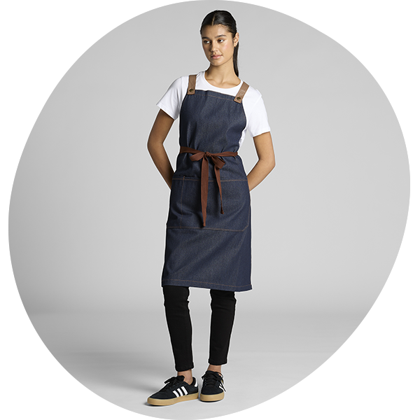 Model wearing a dark denim bib apron with adjustable straps