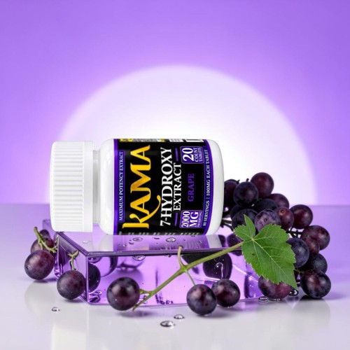 Kama Hydroxy extract bottle with purple grapes on a reflective surface.