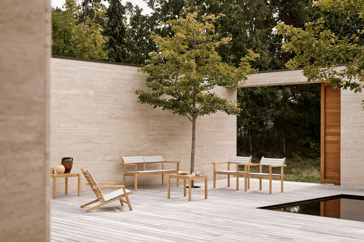 Minimal low-maintenance pool patio with teak outdoor lounge furniture, concrete walls, and simple modern landscaping