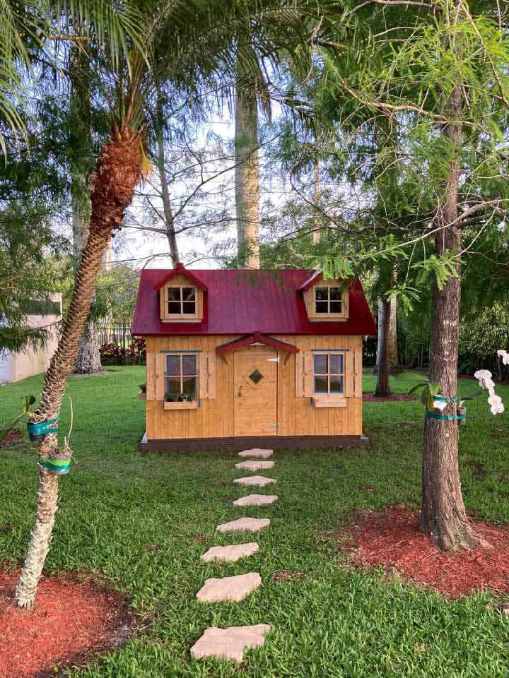Wooden DIY Playhouse with flower boxes and window shutters in the backyard by WholeWoodPlayhouses
