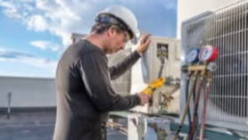 Technician servicing an air conditioning unit on a rooftop.