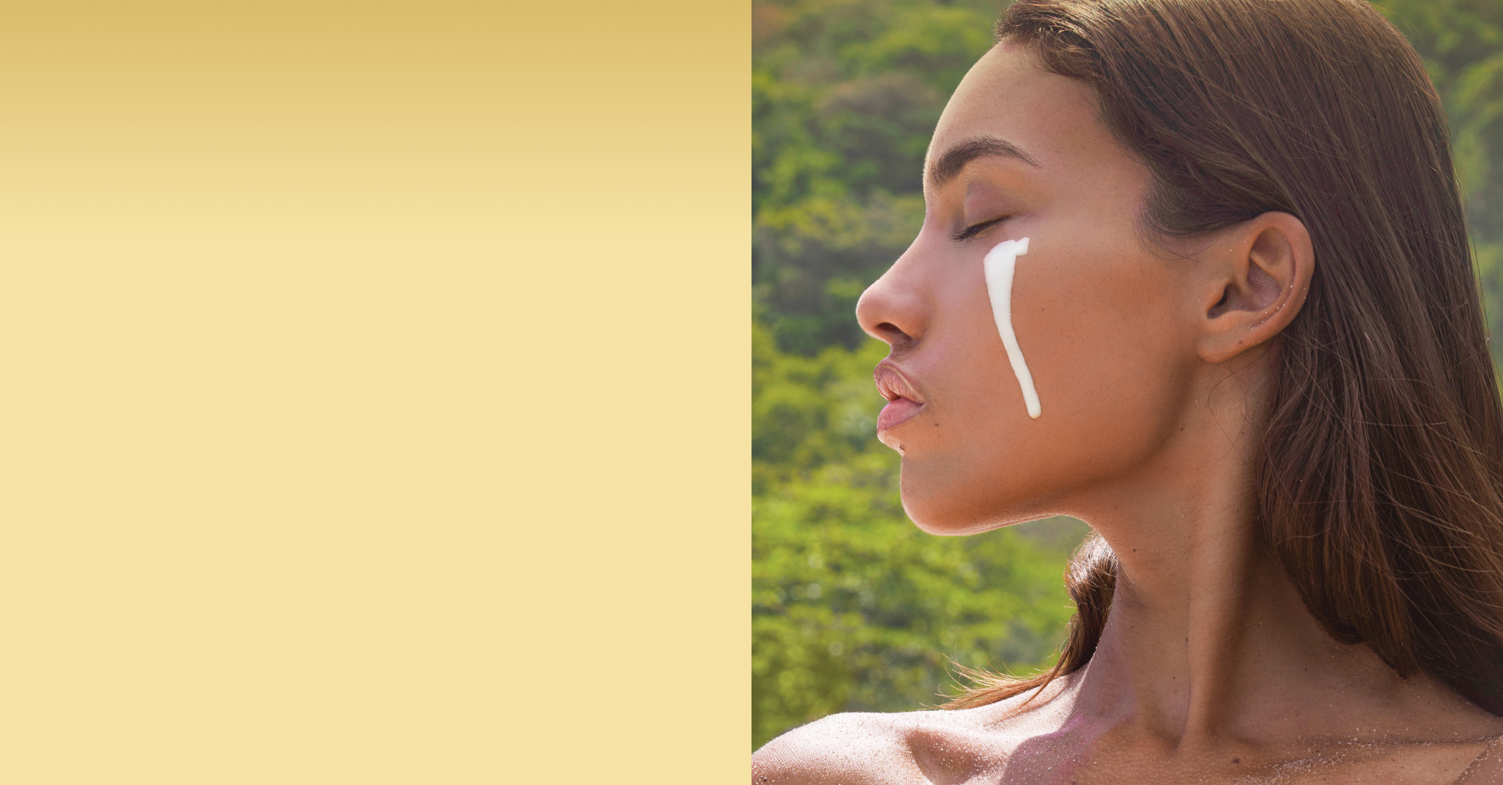 A woman applying skincare product on her cheek outdoors.
