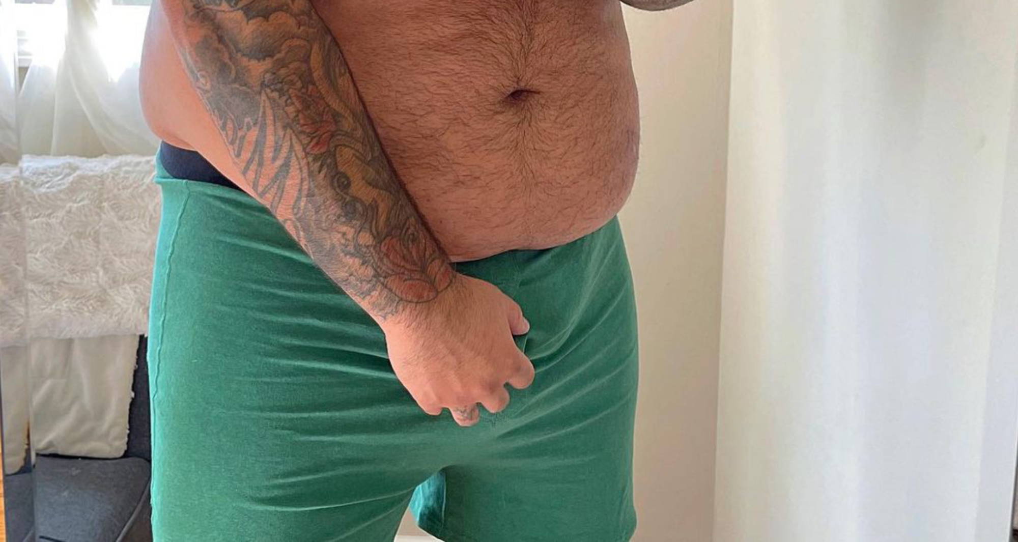  a plus-size man in green boxers with his hand in front of his package
