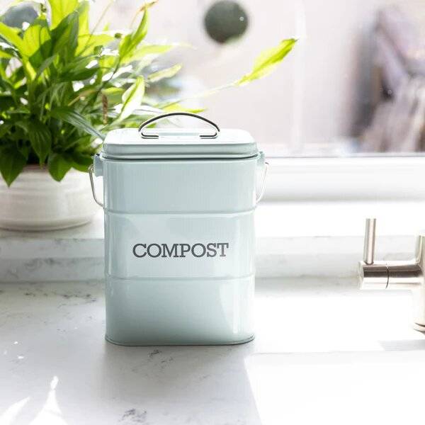 A pale blue food bin on a kitchen surface with the word 'compost' on it, 