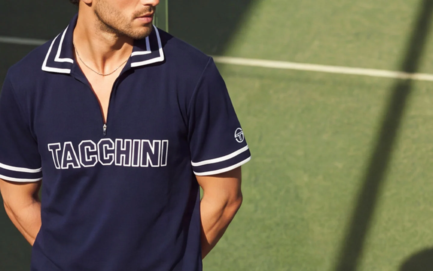 Man wearing a navy Sergio Tacchini polo shirt on a tennis court.