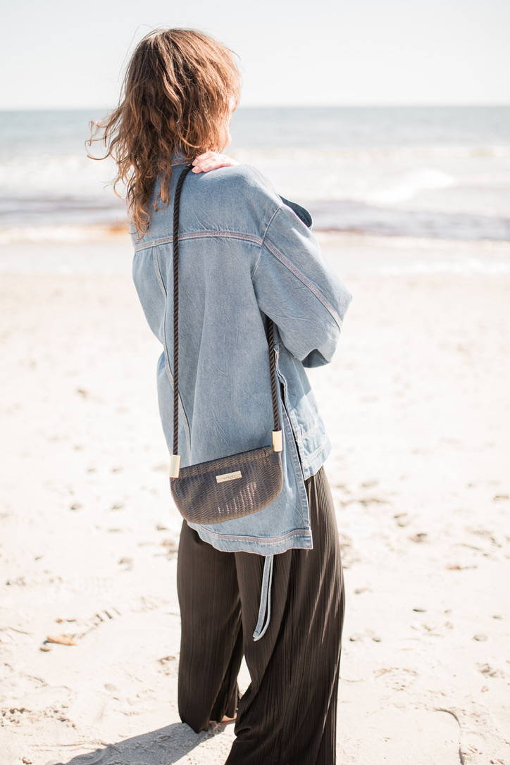 woman wearing black basketweave leather oyster shell bag