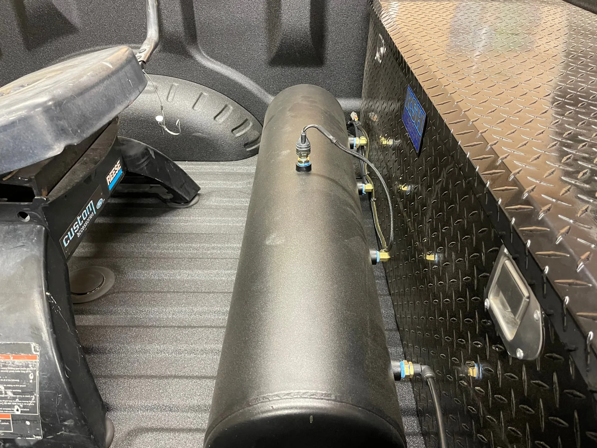 Black air tank mounted in Robert's Ford F450 truck bed between fifth-wheel hitch and toolbox photo 15
