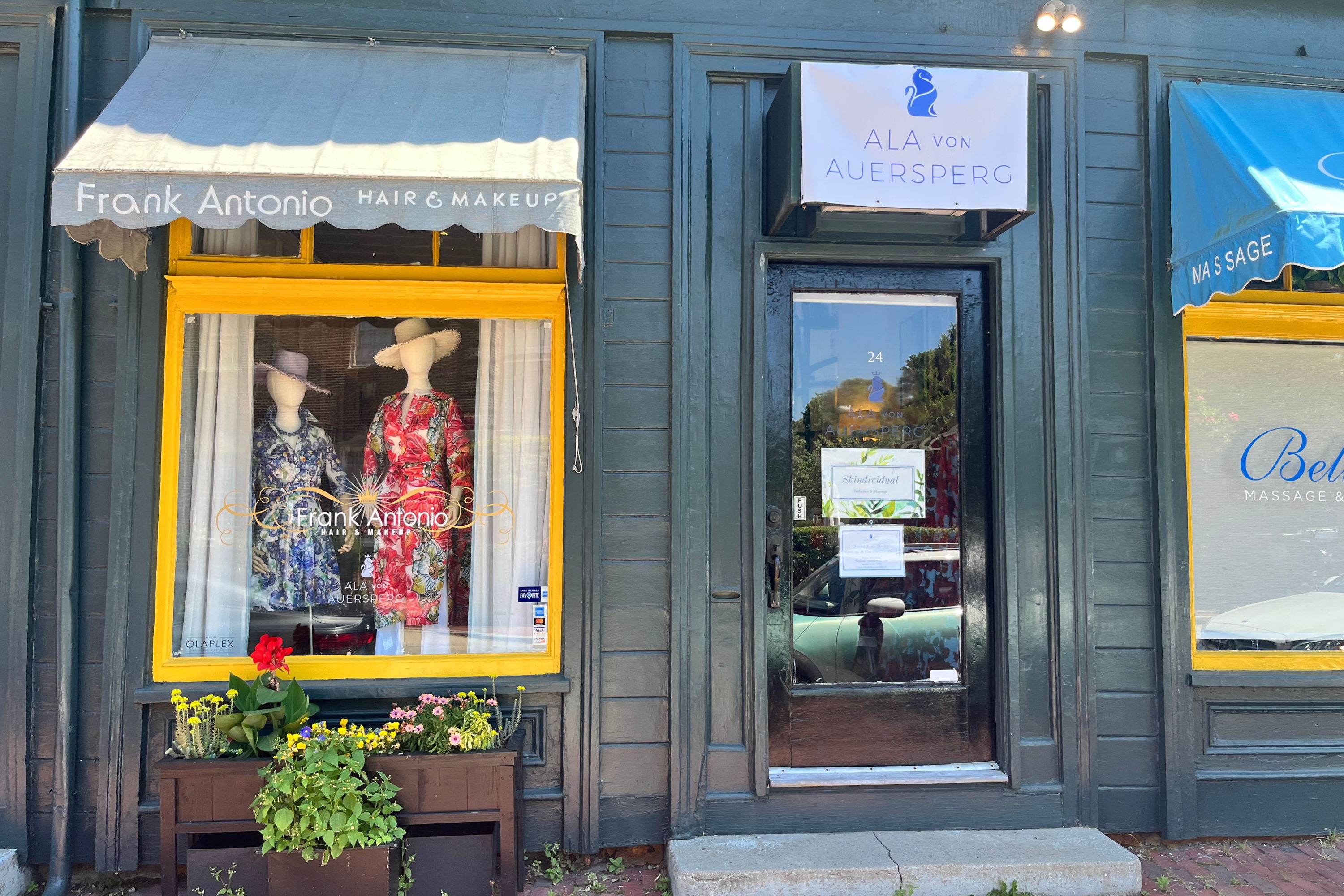 A storefront displaying dresses in the window with colorful awnings.