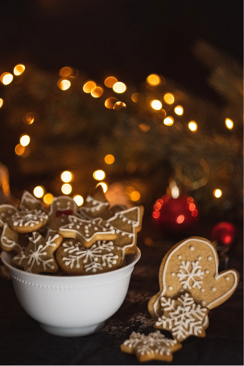 A bowl overflowing with Christmas cookies with twinkle lights in the background.