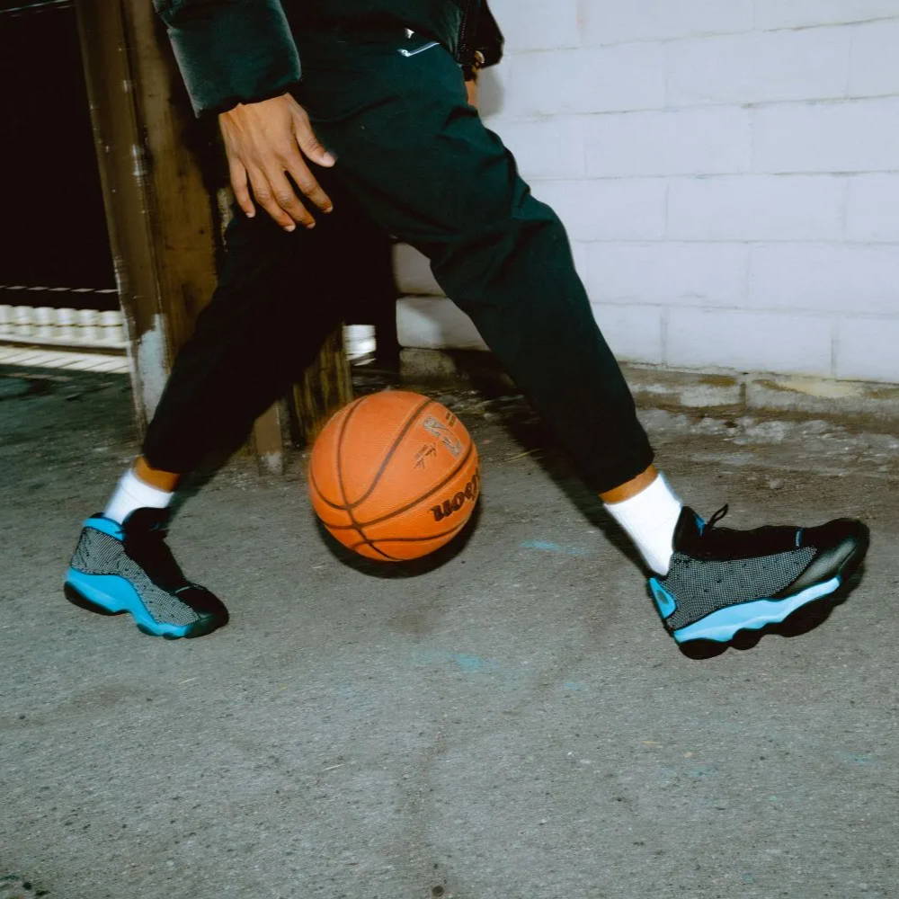 male model wearing aj13 university blue dribbling