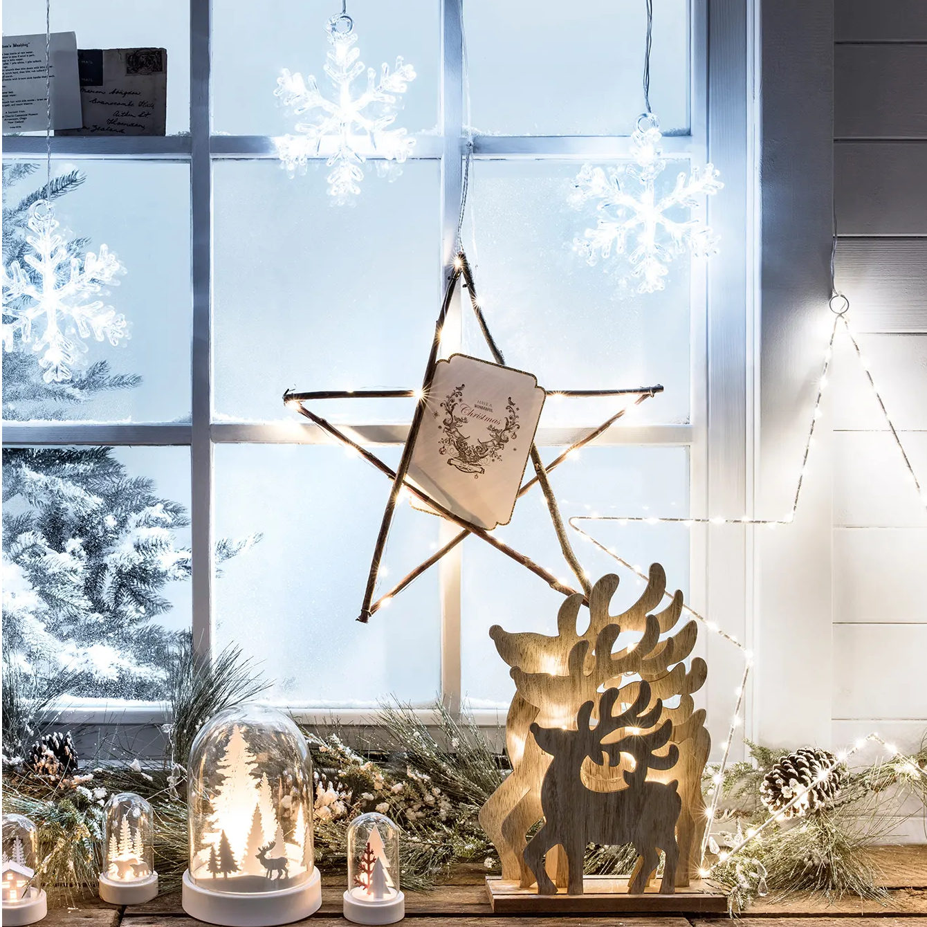 Stockholm Snowflake Christmas Window Light hanging above a window display of wooden ornaments 