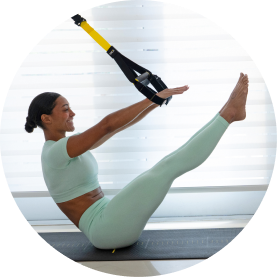 Woman exercising with TRX straps in a bright room.
