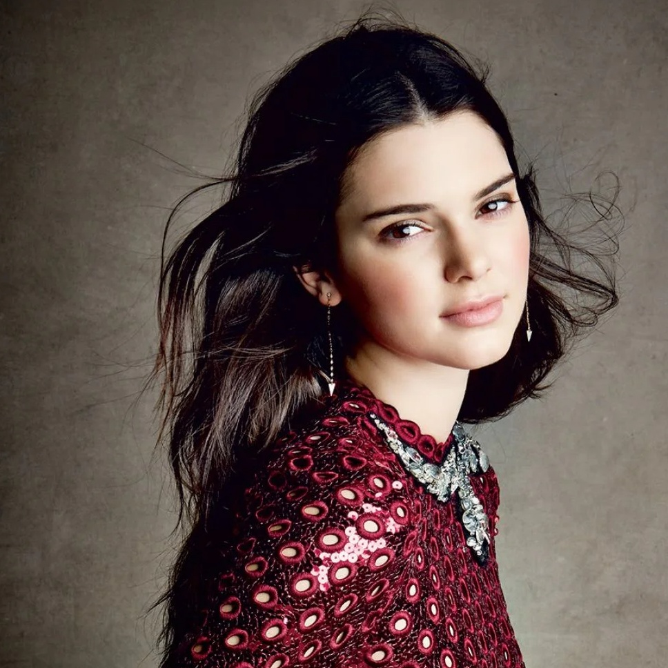 A young woman with dark hair wearing a red dress and earrings.
